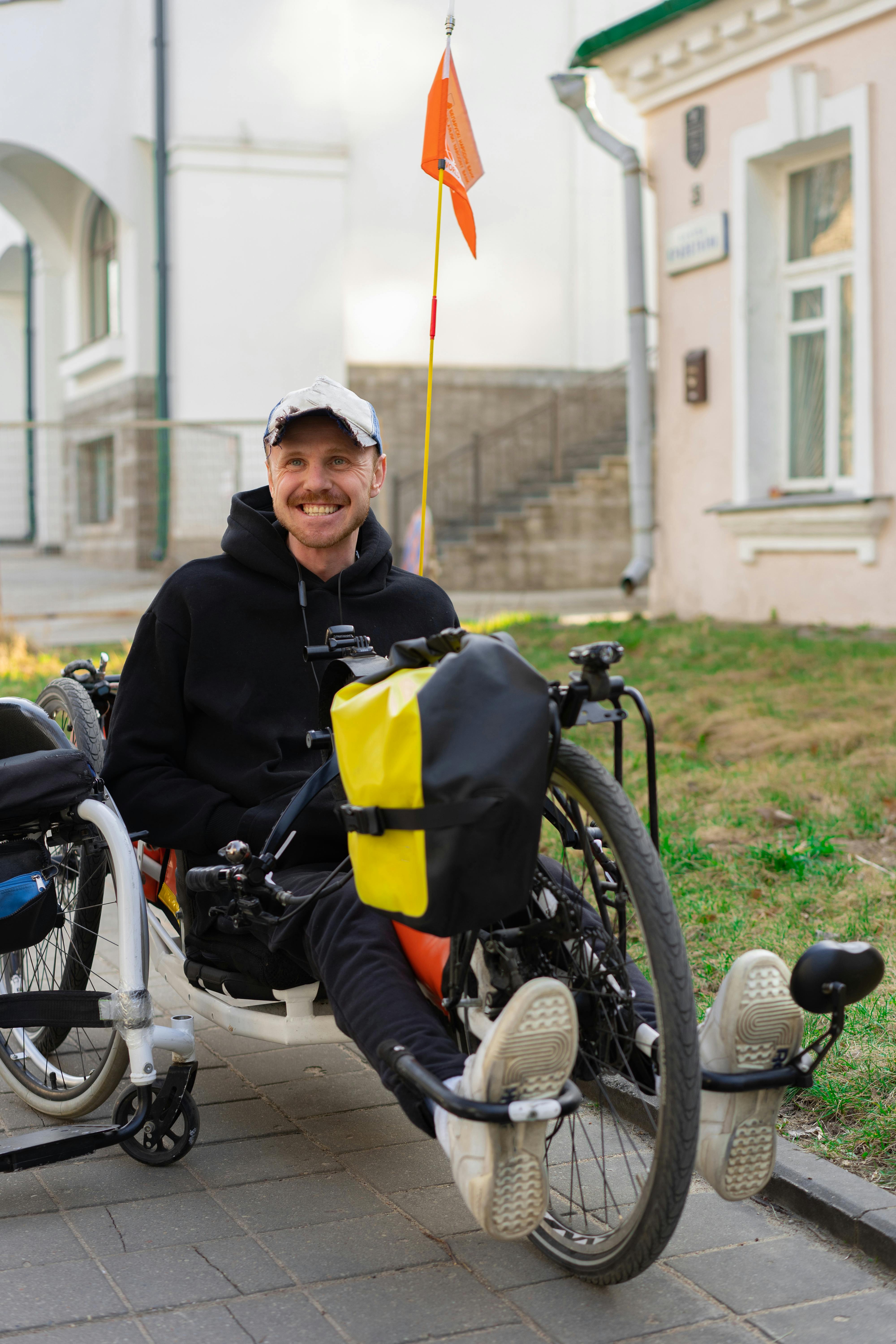 Man in a adapted tricycle who is smiling broadly enjoying his care services.
